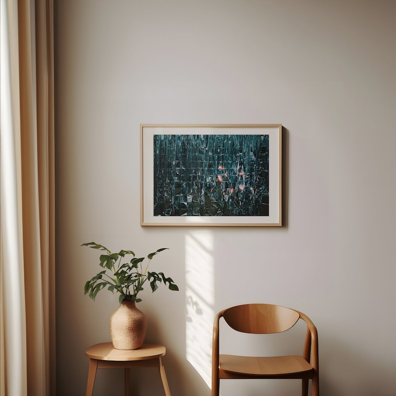 May include: A framed abstract art print with a teal and green color scheme. The print is hanging on a white wall in a room with a wooden chair and a potted plant.