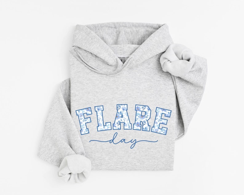 May include: Gray hooded sweatshirt with a blue and white floral print graphic that says "FLARE day" in a collegiate style font.