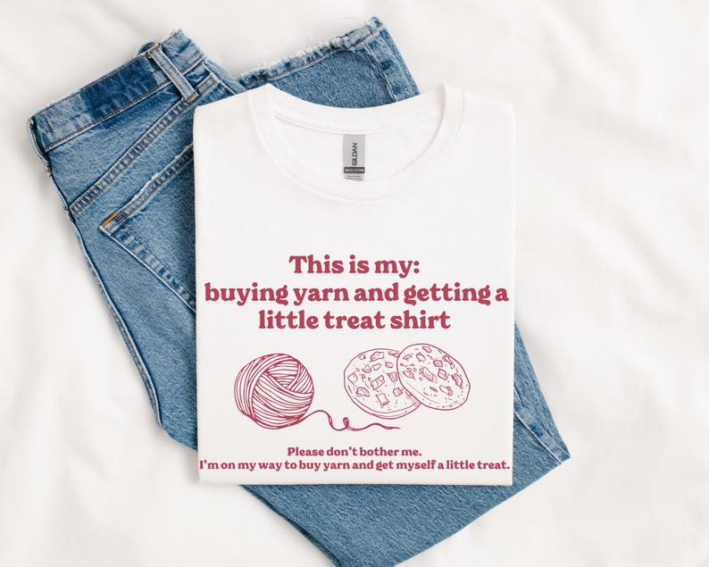 May include: White t-shirt with red text that says "This is my: buying yarn and getting a little treat shirt". There is a drawing of a ball of yarn and two cookies.