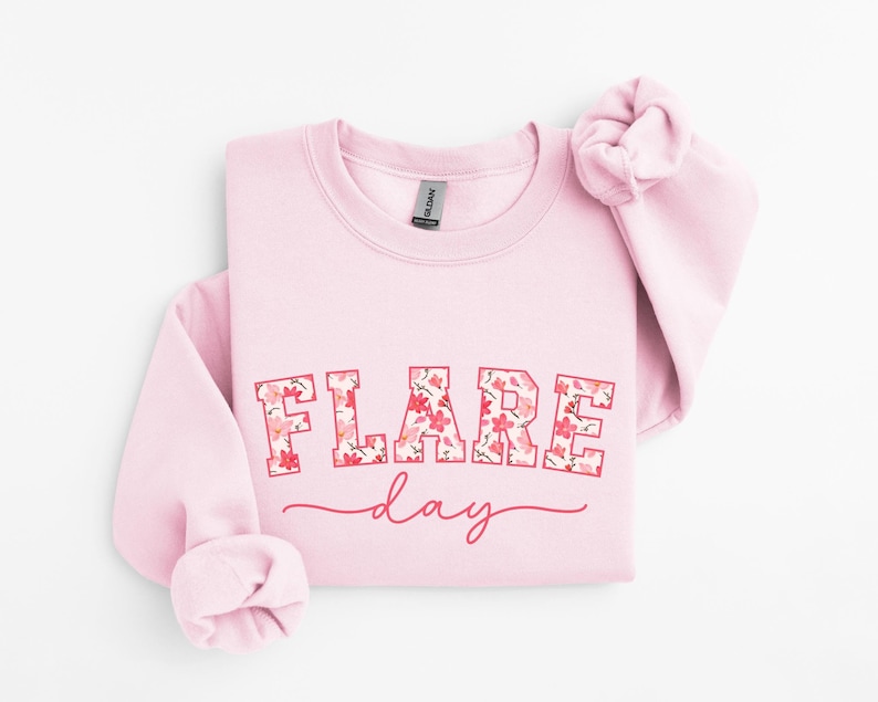 May include: Pink sweatshirt with a floral print design that says "FLARE day" in a collegiate font.