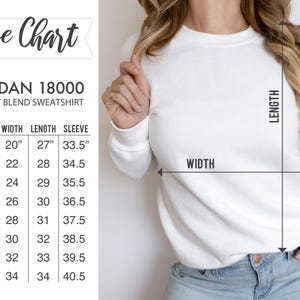 May include: Size chart for a Gildan 18000 heavy blend sweatshirt. The chart shows the width, length, and sleeve length in inches for sizes S through 5XL.