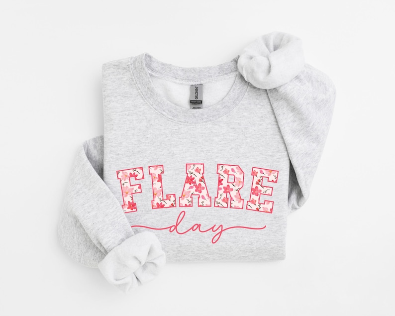 May include: A gray sweatshirt with the text "FLARE day" printed in pink with a floral pattern. The text is in a bold, blocky font.