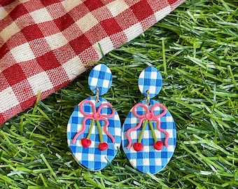 Pendientes de cereza y fresa con lazos rosas y estampado de cuadros vichy blancos y azules. Estilo coqueto y encantador. Arcilla polimérica.