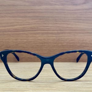 Op de afbeelding: Een bril met een schildpadpatroon montuur in cat-eye stijl en heldere glazen.