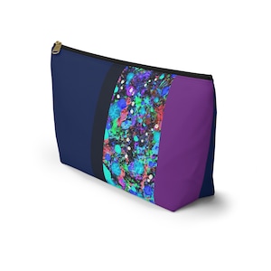 May include: A blue, black, and purple zippered makeup bag with a colorful abstract design. The design features a variety of colors, including blue, green, pink, and white.