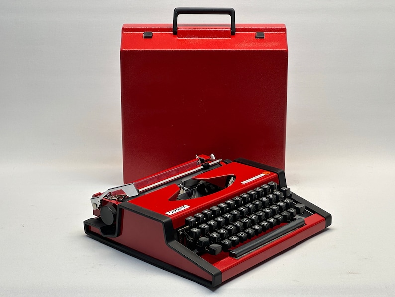 May include: A red vintage Olivetti Lettera 32 typewriter with a black keyboard and a matching red carrying case.