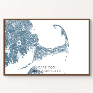May include: A framed print of a blue and white map of Cape Cod, Massachusetts. The map is a stylized representation of the Cape Cod peninsula, with lines and dots representing roads and towns.