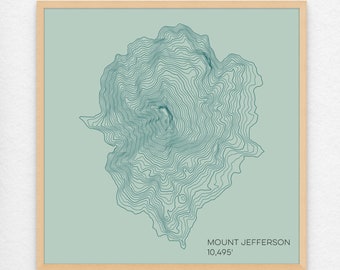 May include: A teal blue topographic map print of Mount Jefferson, with the elevation listed as 10,495 feet. The print is framed in a light wood frame.