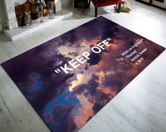 May include: A rug with a cloudy sky design in shades of purple, pink, and blue. The text "KEEP OFF" is printed in white on the rug. The text "IKEA® c/o Virgil Abloh" is printed in white in the bottom right corner of the rug.