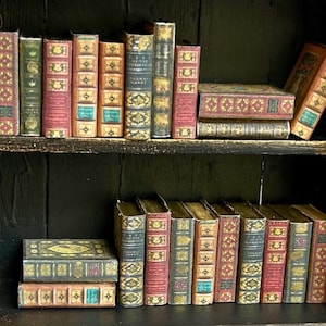 May include: A miniature bookshelf filled with small, antique-style books. The books have various colors, including red, green, and blue, with gold accents. The bookshelf is dark brown, and the books are arranged on two shelves.