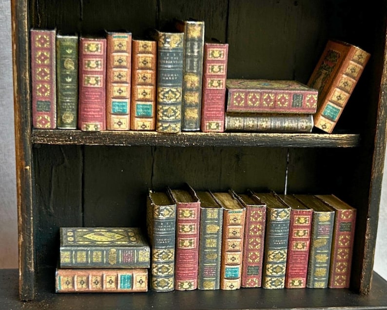 May include: A miniature bookshelf filled with small, antique-style books. The books have various colors, including red, green, and blue, with gold accents. The bookshelf is dark brown, and the books are arranged on two shelves.