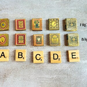 May include: A collection of miniature, decorative books with ornate, colorful covers. The books are arranged in two rows, with Scrabble tiles spelling out letters A through E below. The text "FRONT" and "BACK" are visible.