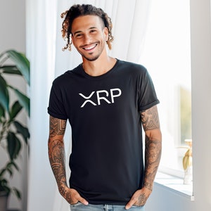 May include: A man with tattoos and dreadlocks is wearing a black t-shirt with the word "XRP" printed in white on the front. He is smiling and looking at the camera.