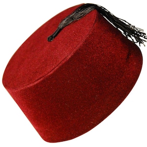 Peut inclure: Un fez rouge avec un dessus plat et un gland noir. Le chapeau est fait d'une matière semblable à du feutre et a une forme cylindrique. Le gland pend du haut du chapeau.