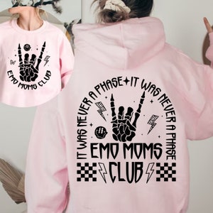 Puede incluir: Sudadera con capucha rosa con un estampado gr&aacute;fico negro que dice "It was never a phase + It was never a phase Emo Moms Club" con un dise&ntilde;o de mano de calavera y rayos.