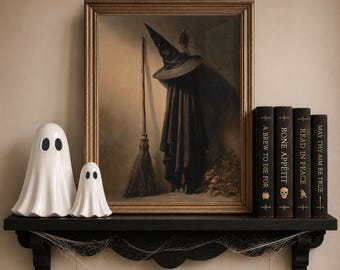 May include: A framed painting of a witch hat, cloak, and broomstick, flanked by two white ceramic ghost figurines and four black books titled A Brew to Die For, Bone Appétit, Read in Peace, and May Thy Aim Be True on a black shelf with cobwebs.
