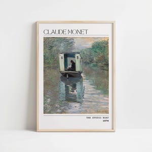 Pode incluir: Uma impressão emoldurada de uma pintura de Claude Monet intitulada "The Studio Boat" que retrata um pequeno barco em um rio com uma pessoa sentada dentro. A pintura é ambientada em um fundo de árvores verdes exuberantes e um céu nublado.