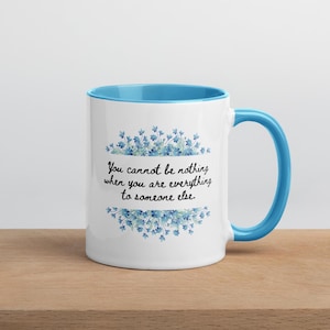 Op de afbeelding: Een witte keramische mok met een lichtblauwe rand en handvat. De mok heeft een bloemenmotief met blauwe bloemen en de quote "You cannot be nothing when you are everything to someone else."