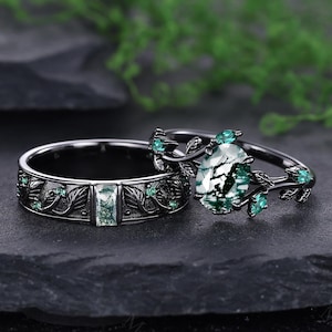 Peut inclure: Ensemble de deux bagues. La bague de fiançailles présente une pierre verte en forme de poire et des détails de feuilles. L'alliance a une pierre verte rectangulaire et des détails de feuilles. Les deux bagues ont des bandes noires.