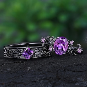 Peut inclure: Une paire d'alliances noires ornées de deux pierres d'améthyste violettes. La plus grande pierre est de forme ovale et la plus petite est carrée. Les anneaux sont décorés d'un motif floral.