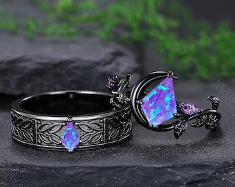 May include: Two black rings with intricate floral designs. One ring features a teardrop-shaped, blue-purple opal. The other ring has a crescent moon design with a large, triangular opal and purple accents. The rings are set against a dark background.