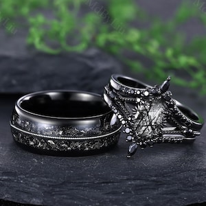 Pode incluir: Dois an&eacute;is pretos. Um &eacute; uma banda com um design texturizado e uma banda prateada. O outro &eacute; um conjunto de tr&ecirc;s an&eacute;is com uma pedra central e detalhes pretos. Os an&eacute;is s&atilde;o exibidos em uma superf&iacute;cie escura.