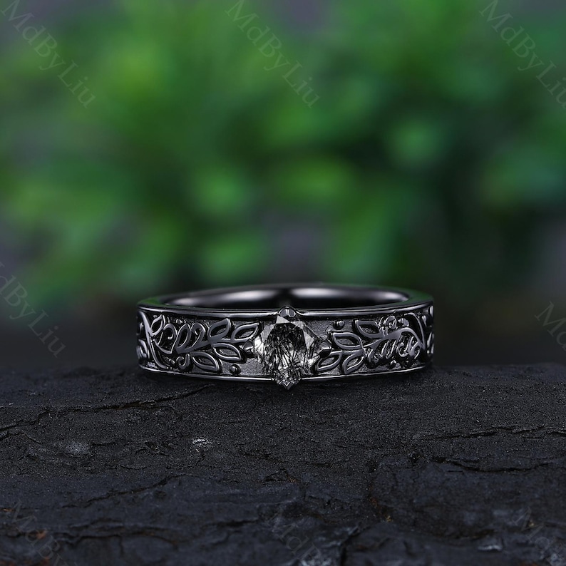 May include: A black ring with a floral design and a single diamond in the center.