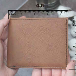 Puede incluir: Una cartera de cuero marr&oacute;n con una superficie texturizada. La cartera mide 11,4 cm por 8,9 cm.