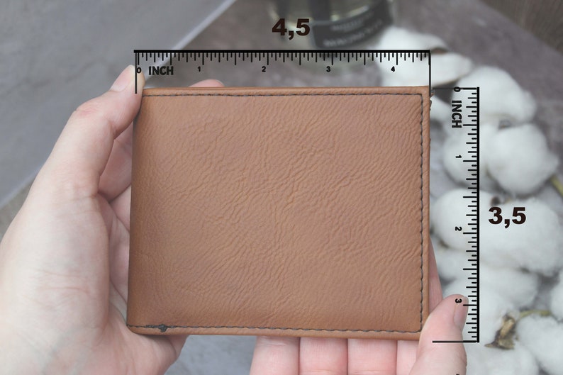 Puede incluir: Una cartera de cuero marr&oacute;n con una superficie texturizada. La cartera mide 11,4 cm por 8,9 cm.