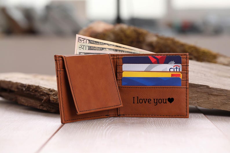 May include: A brown leather wallet with a flap closure and multiple card slots. The wallet has the words "I love you" and a heart symbol engraved on the front.