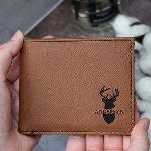Puede incluir: Una cartera de cuero marr&oacute;n con una silueta de ciervo y el nombre "Anderson" grabado en ella.