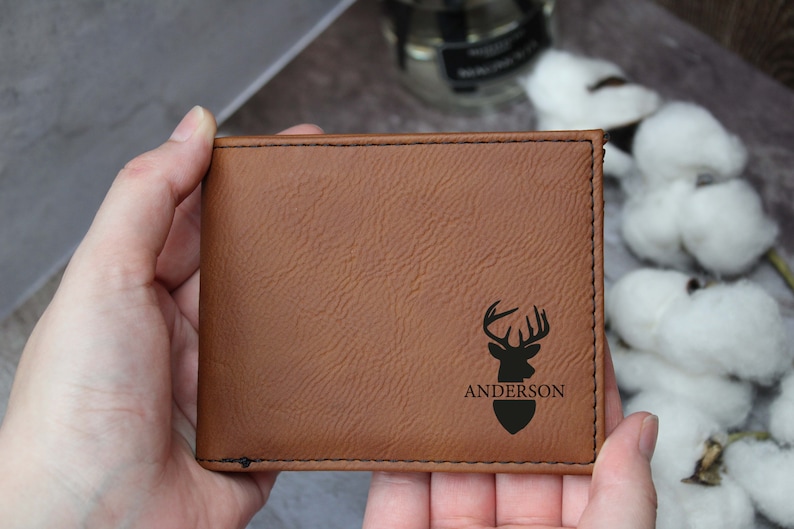 Puede incluir: Una cartera de cuero marr&oacute;n con una silueta de ciervo y el nombre "Anderson" grabado en ella.