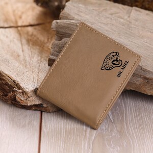 May include: A tan leather wallet with a black jaguar design and the word "MICHAEL" embossed on the front.