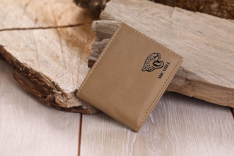 May include: A tan leather wallet with a black jaguar design and the word "MICHAEL" embossed on the front.