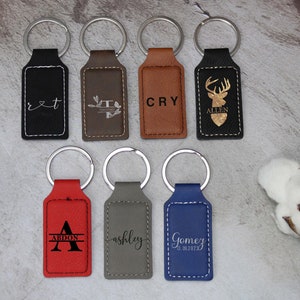 May include: Seven personalized leather keychains with different designs and names. The keychains are black, brown, red, gray, and blue.