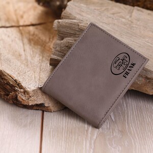 May include: A gray leather wallet with a logo and the name "FRANK" embossed on the front.