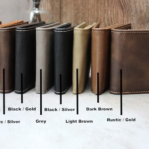 Puede incluir: Ocho carteras de cuero en diferentes colores y acabados, incluyendo cuero crudo, negro con costuras doradas, negro con costuras plateadas, marr&oacute;n oscuro, gris, marr&oacute;n claro y marr&oacute;n r&uacute;stico con costuras doradas. Las carteras est&aacute;n dispuestas en una fila de izquierda a derecha.