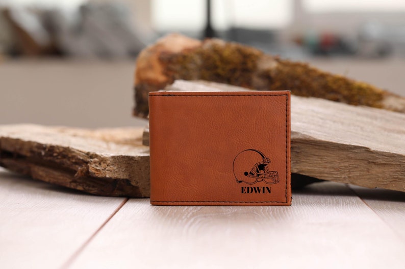 May include: Brown leather wallet with a football helmet and the name "EDWIN" engraved on the front.