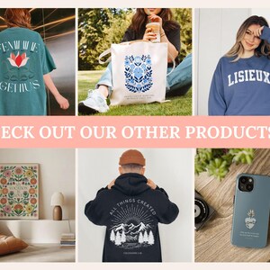 May include: A collection of apparel and accessories including a teal t-shirt with "FEMININE GENIUS" text, a white tote bag with blue floral art, a blue sweatshirt with "LISIEUX" text, a floral wall print, a black hoodie with mountain art, and a phone case.