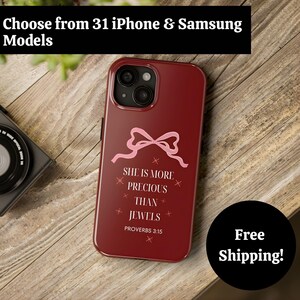 May include: A burgundy iPhone case with a pink bow design and the text "She is more precious than jewels" from Proverbs 3:15. The case is on a wooden surface. The top of the image has the text "Choose from 31 iPhone & Samsung Models".