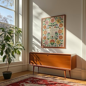 Saint Thérèse of Lisieux Catholic Wall Art Poster in Scandinavian Folk Floral Design with the phrase 'My vocation is love" centered. Around the text are folk-nspired flowers in hues of green, peach, salmon, pink, and yellow. The framed Catholic Quote Poster hangs on a wall in a mid-century modern living room.