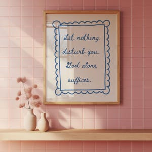 Puede incluir: Una impresión enmarcada con fondo blanco y borde azul. La impresión presenta una cita en una fuente decorativa: "Que nada te perturbe. Dios solo basta."