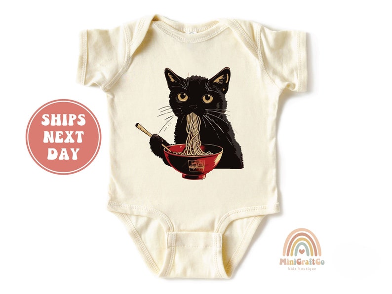 May include: A cream colored baby onesie with a black cat eating noodles from a red bowl. The cat is wearing a red collar and has a black nose and whiskers.