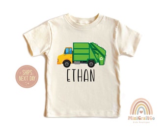May include: A white short-sleeved t-shirt with a green and yellow garbage truck graphic and the name "ETHAN" printed in black below the truck.