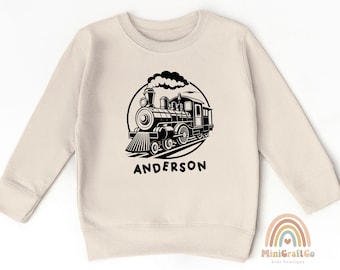 May include: A cream colored sweatshirt with a black and white illustration of a train engine with the name "Anderson" printed below.