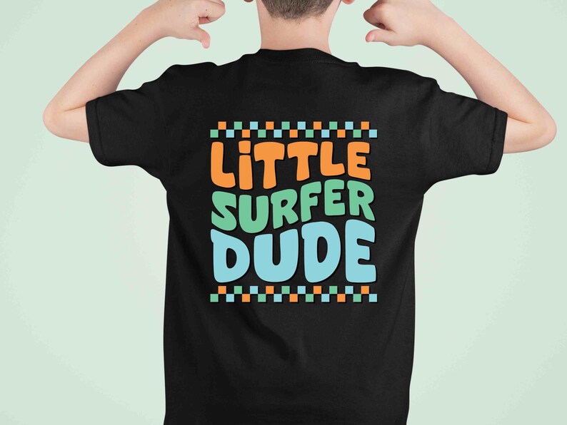 K&ouml;nnte beinhalten: Schwarzes T-Shirt mit dem Text "Little Surfer Dude" in bunten, stilisierten Buchstaben. Der Text ist von einer Reihe kleiner orangefarbener, gr&uuml;ner und blauer Quadrate eingerahmt.