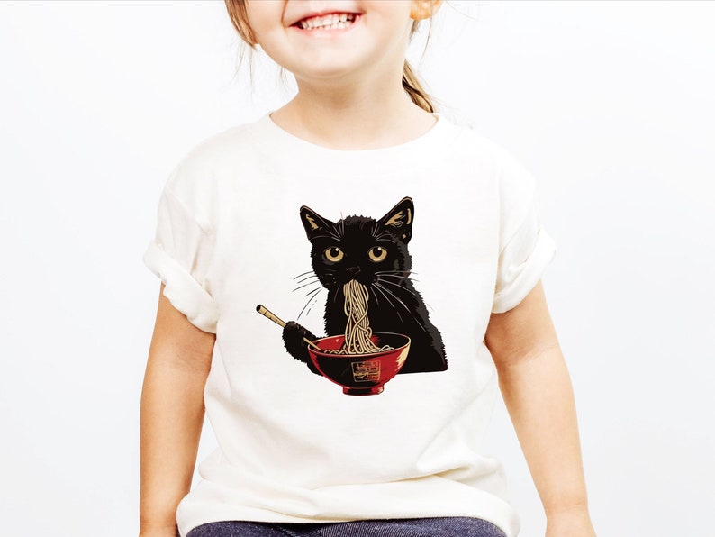 May include: A white t-shirt with a black cat eating noodles from a red bowl. The cat has a serious expression on its face.