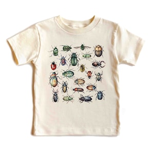 May include: A white organic cotton t-shirt with a colorful print of various beetles. The print features a variety of beetle species, including green, blue, red, and brown beetles.