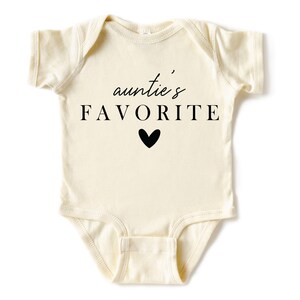 May include: A cream-coloured baby onesie with short sleeves and a black graphic that reads "auntie's FAVORITE" with a small black heart.