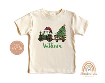 May include: A green tractor with a red Santa hat pulls a wagon with a decorated Christmas tree. The tractor has a personalized name, "William", printed on the front.